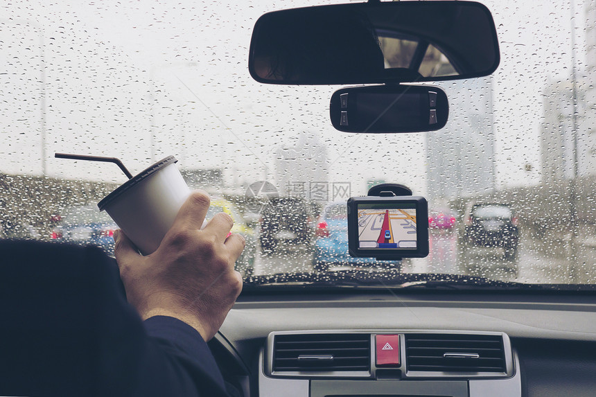 斯林拉特下雨男子驾驶汽车时使用导航员在雨天举着咖啡杯速度图片