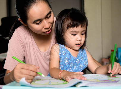 女孩快乐的亚洲母亲帮助女儿在放学后做家庭作业教义概念父母图片