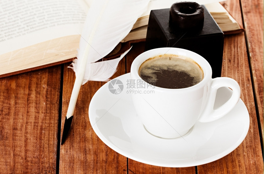 黑色的咖啡杯配有钢笔和木制背景书上的墨水意大利语碟子图片