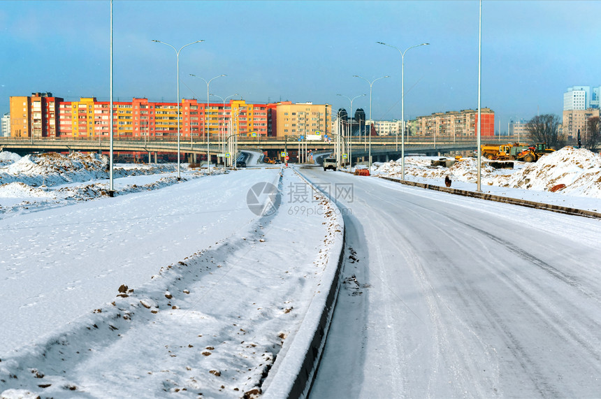 通往城市的雪覆盖道路通往城市的雪覆盖通道路过山和冬季高楼大的交叉路口过山公和高楼建筑速公路造街道图片