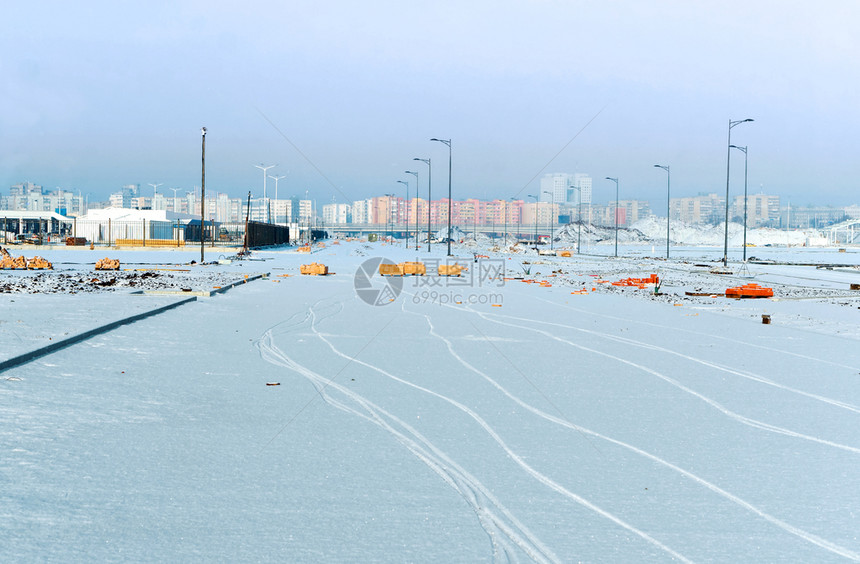 通往城市的雪覆盖道路通往城市的雪覆盖通道路过山和冬季高楼大的交叉路口过山公和高楼建筑寒冷的天空季节图片