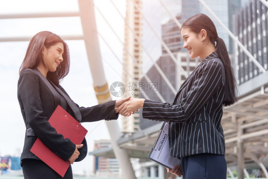 两名商业妇女在户外与交通背景商业和联系协议概念的交往背景发生手握关系工作商人女图片