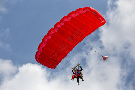 兵乒球运动员积极的串联伞兵降落在蓝天的红色降落伞串联兵降落在红色伞跳飞行背景