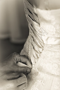 垂直的棕褐色新娘结婚礼服的丝带紧贴准备婚礼的Sepia新娘背部图片
