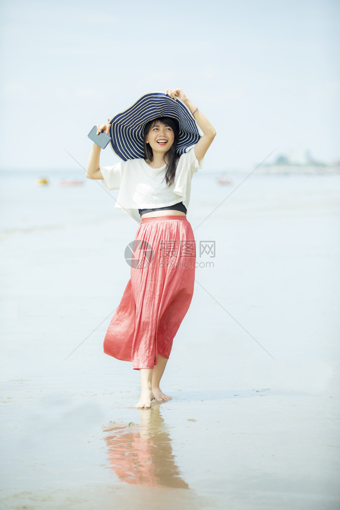 请享用戏服在度假海滨滩上快乐的年青美丽亚洲年轻女露齿的图片