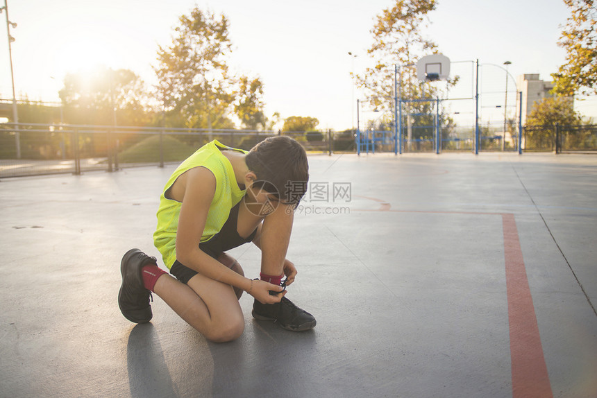 小男孩把鞋带系在上青少年汗篮球图片