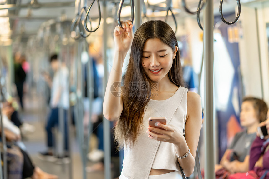 乘坐地铁看手机的年轻女孩图片