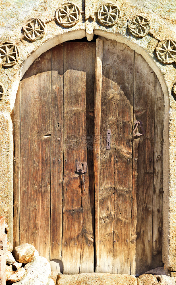 古老的木门有石板和金属铁铸锁Antique拱木门有石板和中间的金属锁Antique框架外部的结构体图片