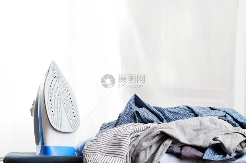 电气干净的蓝色铁在洗衣店熨烫一大堆服的蓝铁在室内图片