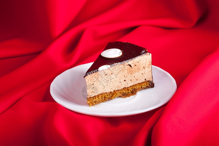 浅色丝绸红色丝绸背景的盘子上美味巧克力蛋糕浅色焦点礼物美味的红色背景