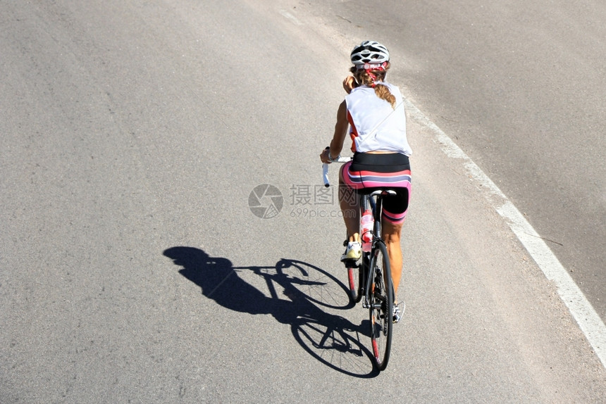 自行车骑的女运动员在开阔的道路上沥青移动巷道图片