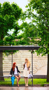 分支机构时尚2个女孩在雨季的公共汽车站高图片