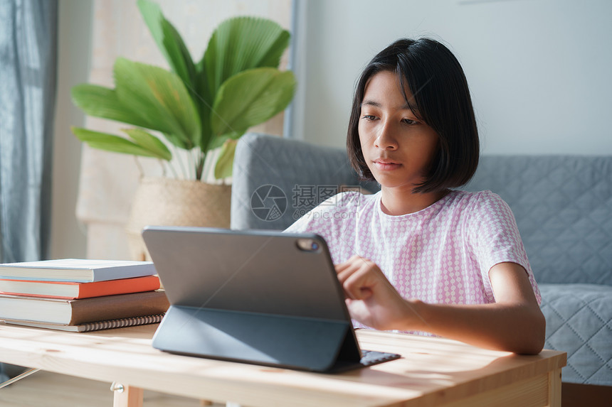 在家上学的亚裔女孩正在网上与教师一起学习平板电脑并在家里清晨和阳光下做家庭功课在中线学习概念家中进行线学习亚洲人女士知识图片