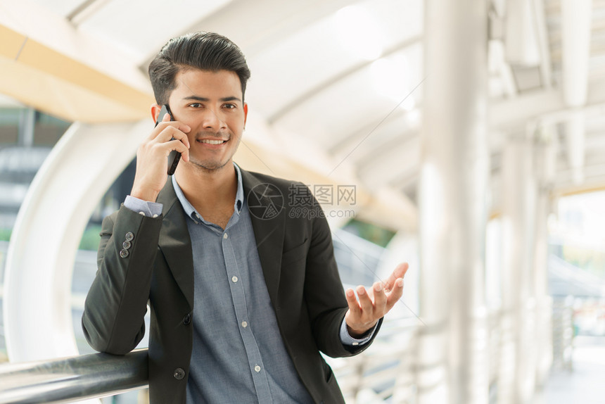 常设专业的现代站在办公室外亚洲青年商人肖像一个穿着这么聪明的西装用智能手机对商业话说笑声图片
