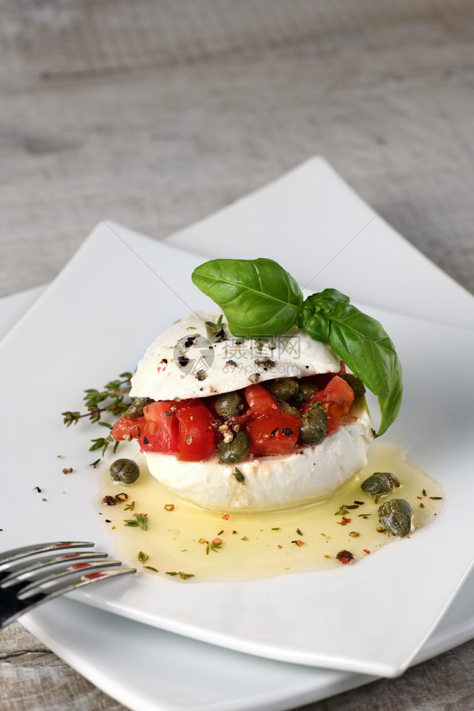 Mozzarella塞满西红柿的披风季节香料和油中的美食盘子服务图片