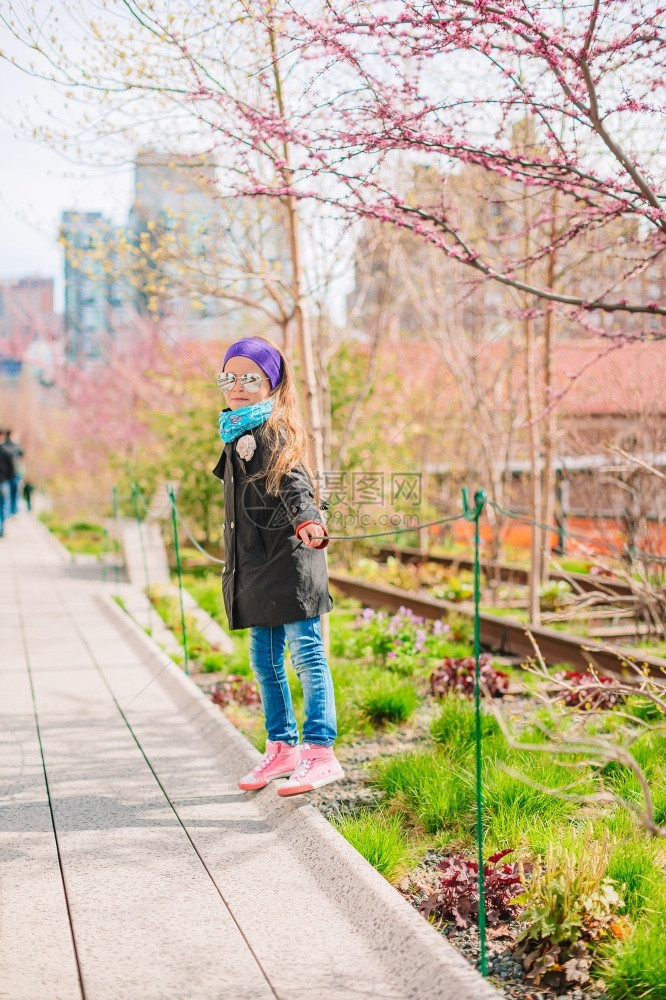 中央可爱的小女孩享受纽约公共高线城市园中阳光明媚的一天美丽小女孩享受纽约高线上的阳光天气地标历史图片
