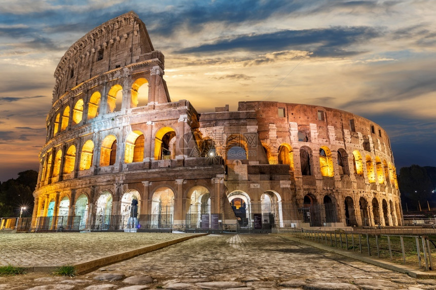 日落意大利出时云下闪光的罗马竞技场在下面罗马的图片