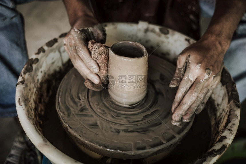 在陶器车轮上工作的匠手掌选择焦点重在职的黏土图片