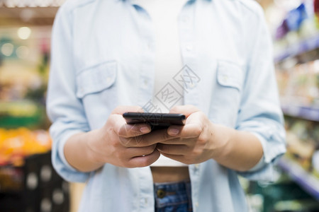 沟通妇女浏览智能手机杂货店商业市场图片