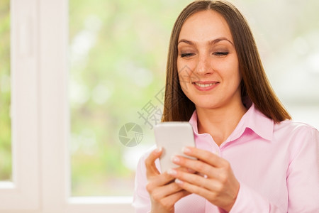 笑脸女商人在她的手机上打短信肖像互联网图片