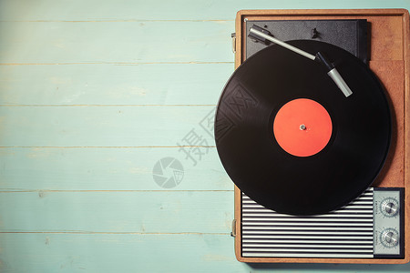 在锈木制桌子顶视图和复制空间上有黑乙烯唱片的老式留声机七十年代转盘专辑背景图片