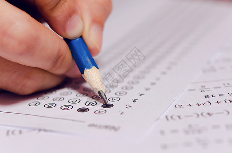 手握单杆课堂学生手握铅笔在答题单和数学问上写有选择的作考试学校的生进行测以及演讲注意力背景
