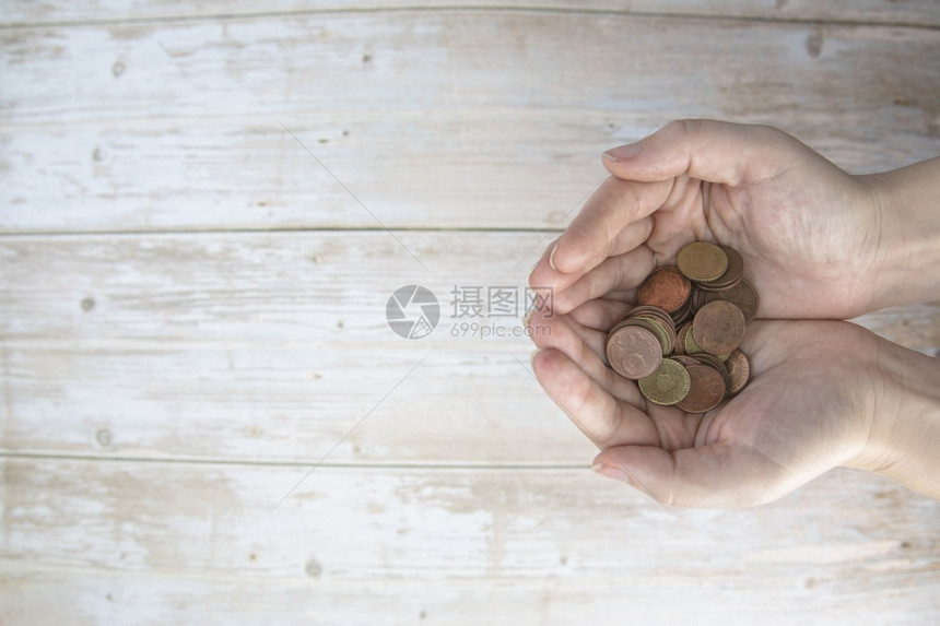 银行木头手拿着一堆钱欧元硬币在木背景上捐赠储蓄筹款慈善家庭财务计划概念金融危机顶视图复制空间文本的手拿着一堆钱欧元硬币在木背景上图片