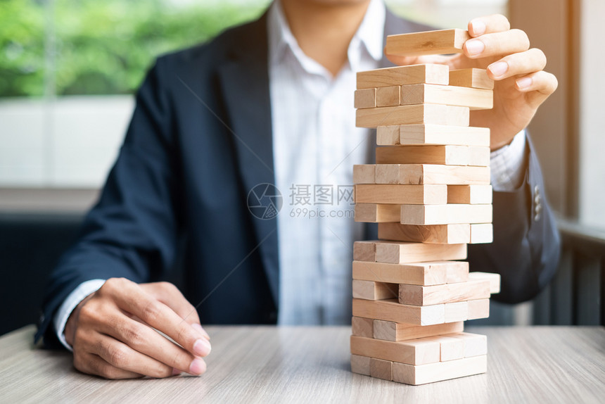 游戏组织商人手在塔上放置或拉动木块业务规划风险管理解决方案和战略概念帕努瓦图片
