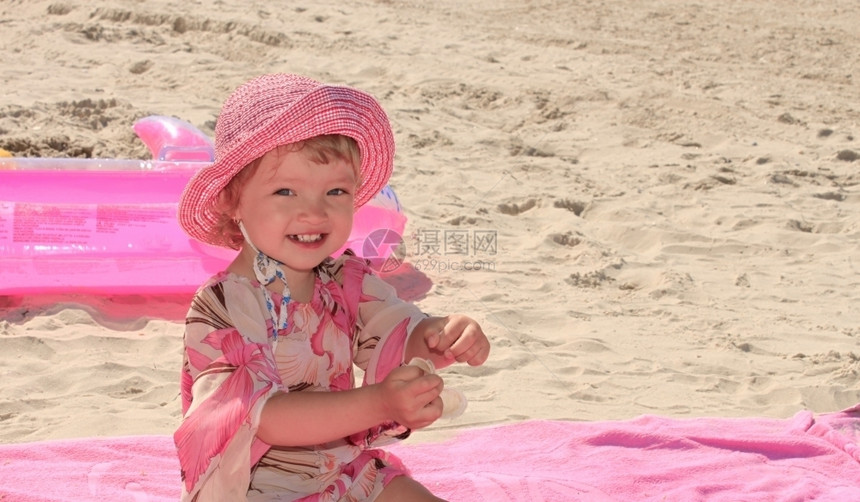 婴儿一个小女孩在粉红环境中桑迪海滨夏天松弛图片