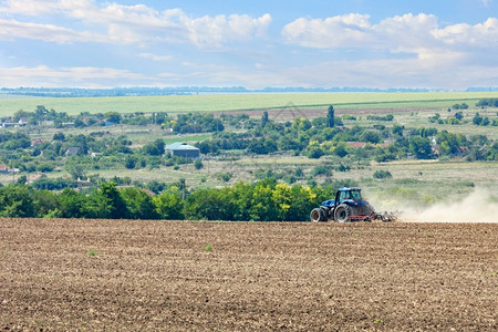 场地庄稼田野中的拖拉机在收割后用金属圆盘耕种土壤田地中的拖拉机在收割后耕种土壤乌克兰培育高清图片素材