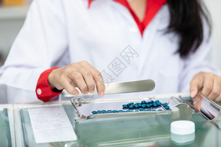 制服泰国药店柜台的亚洲女药剂师物计数和包装盒架子化学高清图片素材