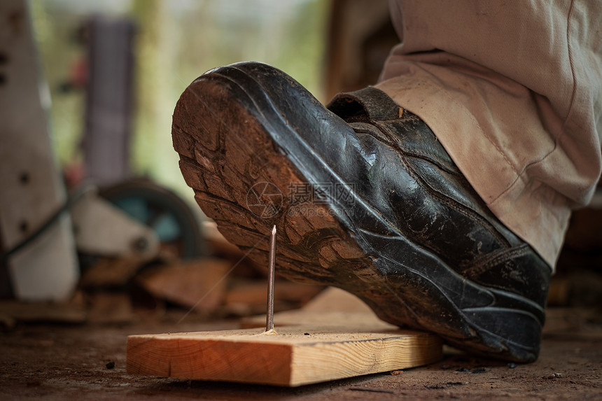 危险工匠在建筑区用安全鞋踩板木上钉子的工人别针建造图片