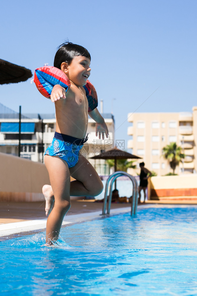 娱乐俏皮请享用可爱的年轻男孩跳进游泳池度假玩乐的时候图片