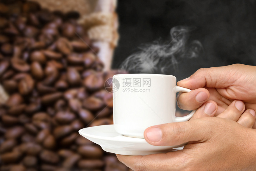 浓咖啡抽烟目的男人手握着白咖啡杯喝蒸汽或热饮喝着茶杯走剪条路图片