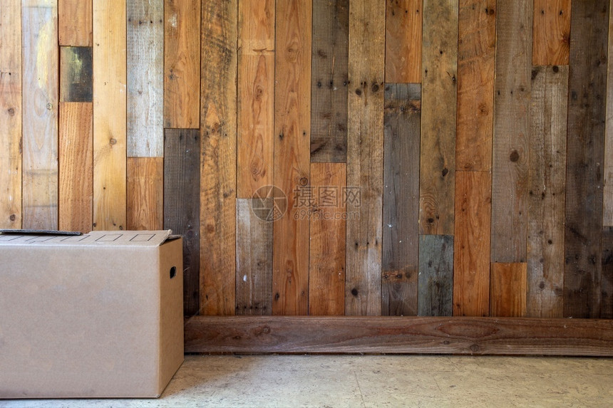 拆包腿平坦的纸板移动箱在空房间里有木墙背景和复制空间搬进新公寓或房子概念复古设计空间文本纸板移动箱在空房间里有木墙背景和复制空间图片