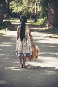 手拿泰迪熊的孤单女孩背影背景图片