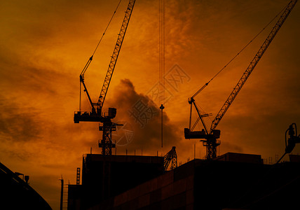 活动戏剧在高楼建筑上造起重机在黄昏日落时用橙色天空和云状的巨型橙色天空建造高楼起重机建造商业筑或城市背景共区城市的背景图片