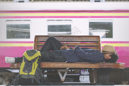 疯了火车年轻男子旅行者睡觉在火车站的轮椅上等候火车去旅行度假离开天户外背景