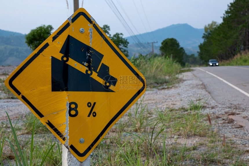 信息破碎的交通号警告尖锐的公路标志使前方道路在背景绿草上倾斜8的坡度运输图片