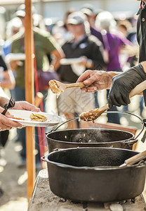 酱锅人们在铁制土烤炉的一条线上提供食物美图片