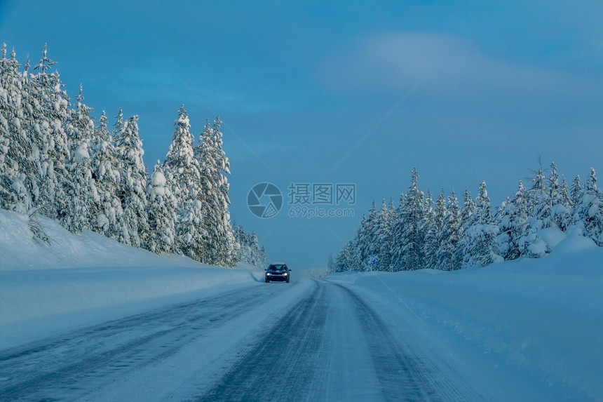 乡间公路在雪林的郊区高速公路上的一辆孤车LonelyCar在雪林中的CownyForest霜下雪的树图片