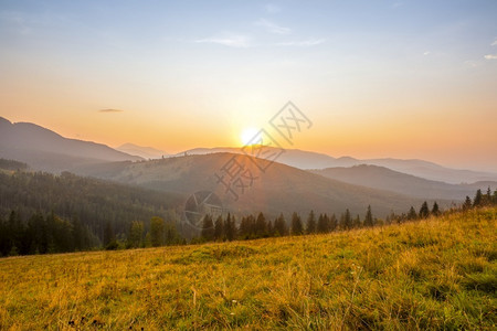 绿色太阳落下在一个无云的天空中在山顶之上太阳在夏日山上升起天空没有乌云日落户外背景图片