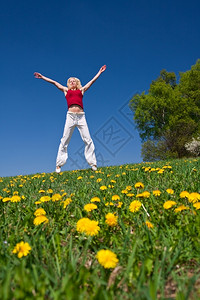 快乐的女士年轻子在鲜花草地上玩得开心飞行图片
