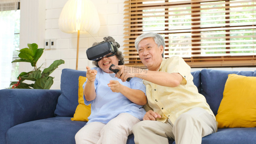 陈年眼镜游戏高龄的亚裔夫妇在家庭客厅玩虚拟现实耳机使用数字平板电脑并带有快乐情绪退休生活方式和技术等幸福感退休生活方式和技术图片