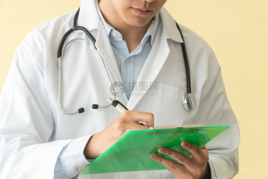 医生在绿色剪贴板上撰写健康报告图片