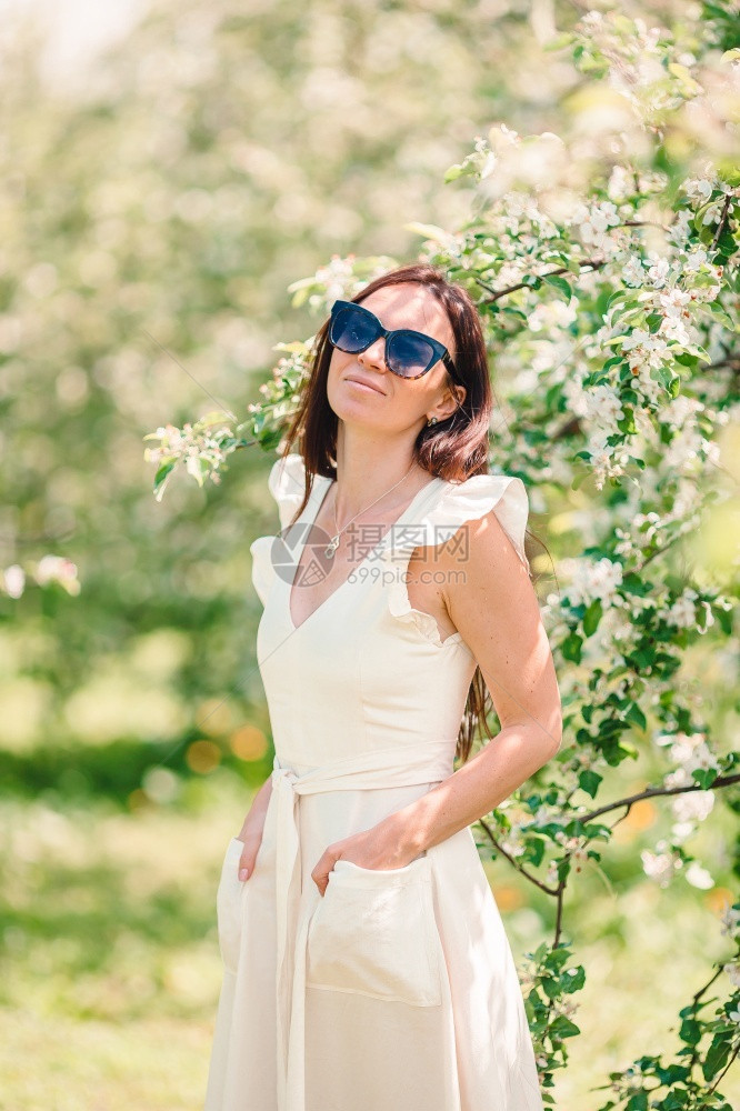 穿着白裙子的美女在春樱桃花园里闻着香味春樱花园里闻着香味的美丽女户外假期复活节图片