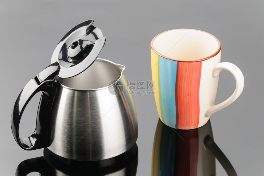 灰色镜面背景咖啡杯附近带黑色塑料盖的不锈钢咖啡壶灰色镜面背景上带咖啡杯的壶厨房推放图片