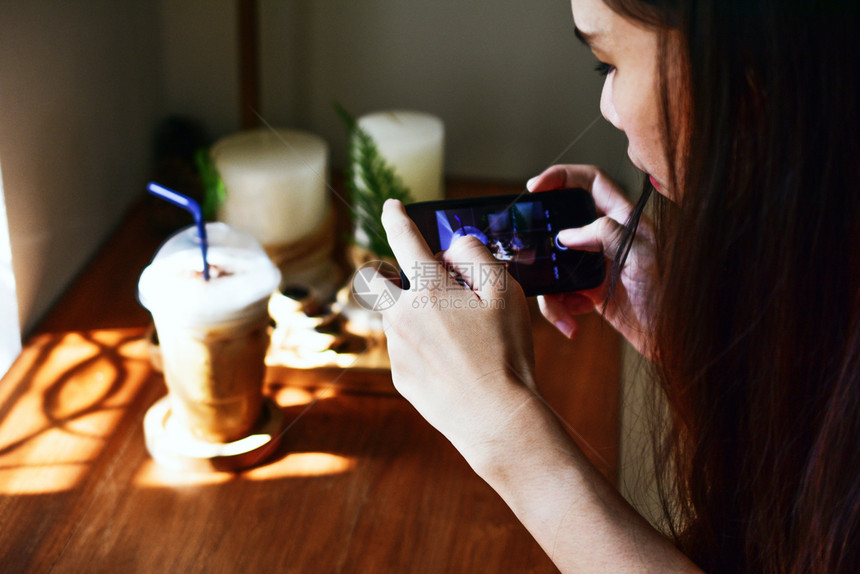 放松使用智能电话的人在木板上拍摄咖啡的照片潮人展示图片