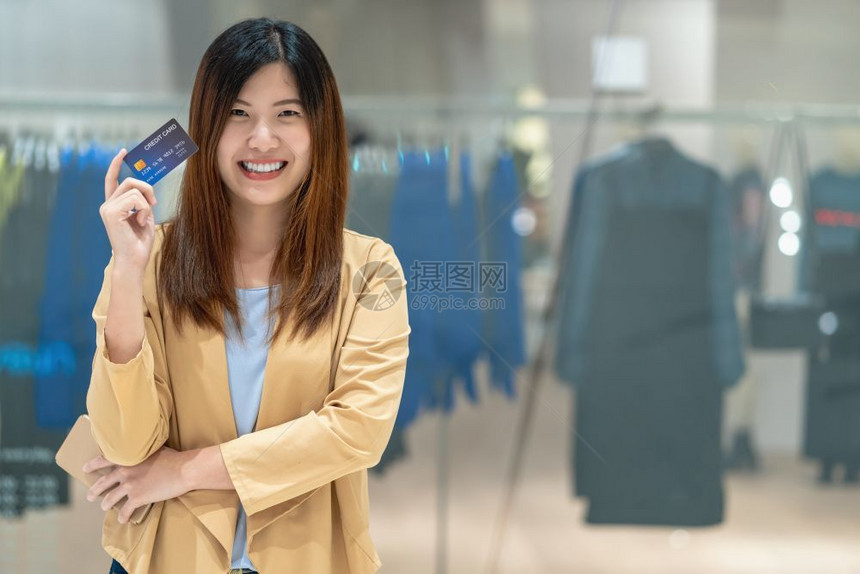 保持银行利用带有智能手机的信用卡在百货商店通过服装铺背景技术资金钱包和在线支付概念购物的亚洲妇女肖像信用卡以及智能移动电话进行线图片