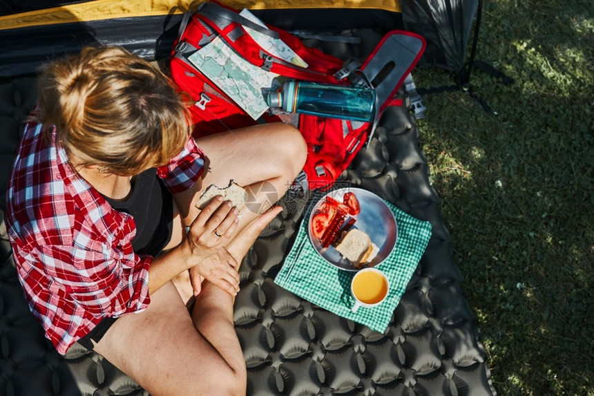 远足在露营地帐篷旁坐着早餐的妇女积极在靠近自然户外的地方过暑假难民营生活概念女积极度暑假士闲暇图片